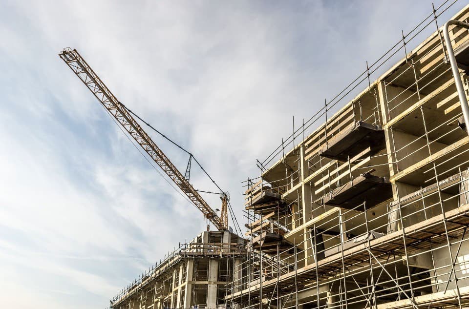 Multi-story building under construction with yellow crane and scaffolding