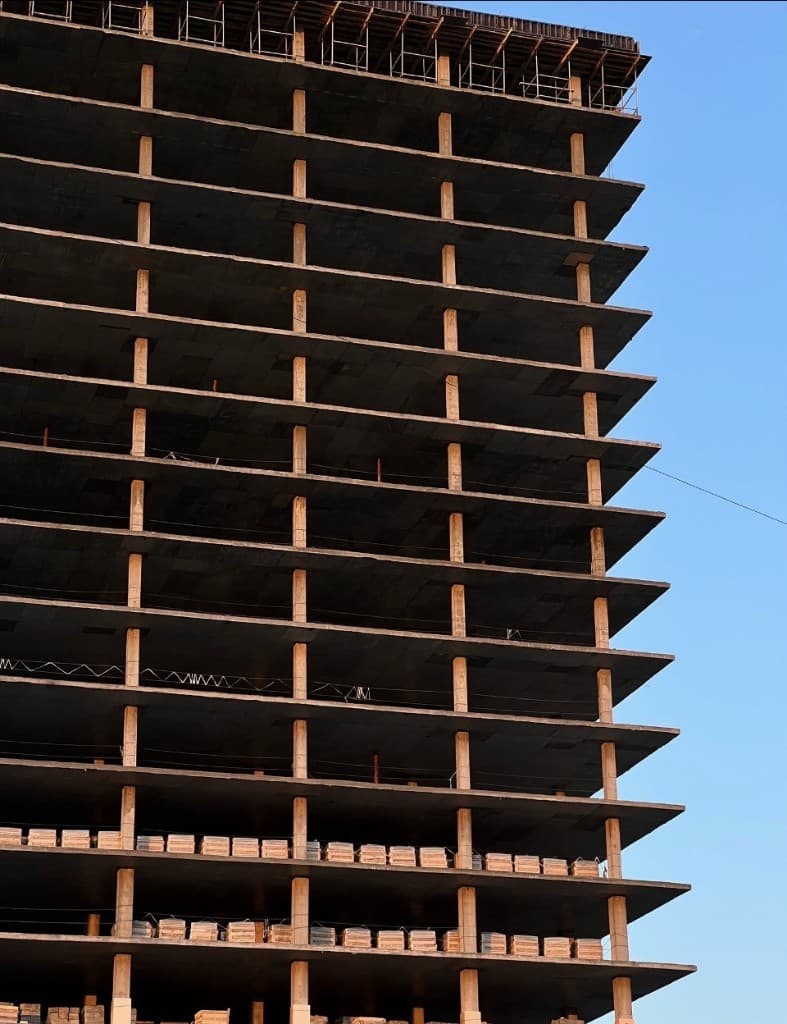 Tall concrete structural skeleton rising against clear sky
